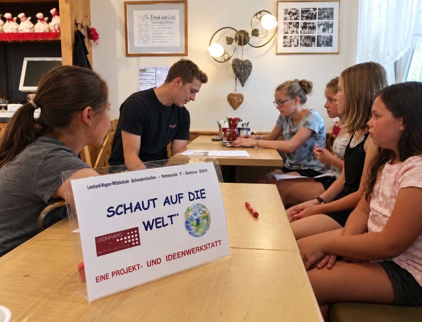 Schülerinnen und Schüler tauschen sich am Tisch zum Projekt Schaut auf die Welt aus.