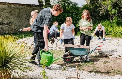 Schülerinnen und Schüler arbeiten gemeinsam mit Gartengeräten im Zukunftsgarten der HAK und HAS Wiener Neustadt.